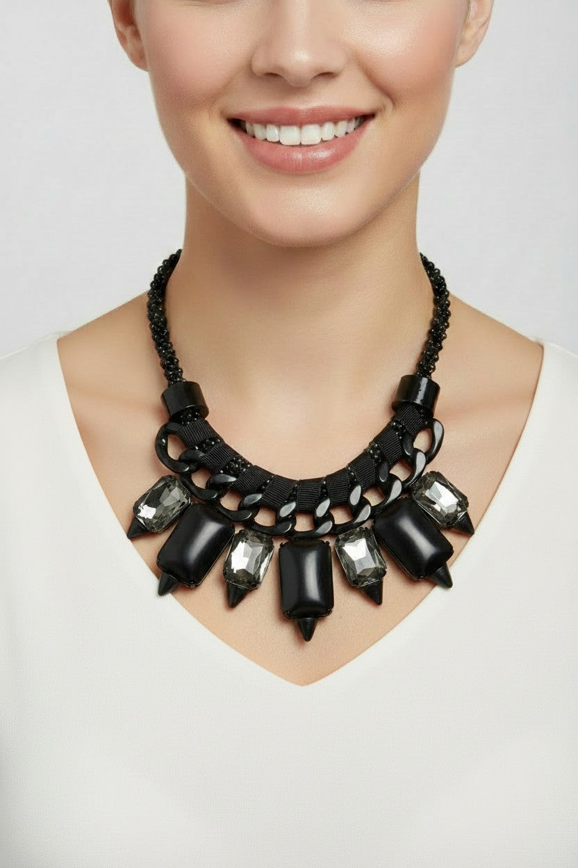Chunky black chain statement necklace interwoven with grey ribbon trim featuring smoky faceted crystals and stark white resin stones