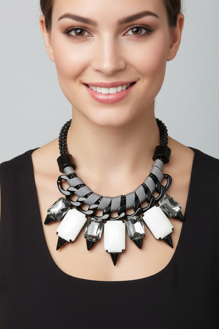 Chunky black chain statement necklace interwoven with grey ribbon trim featuring smoky faceted crystals and stark white resin stones