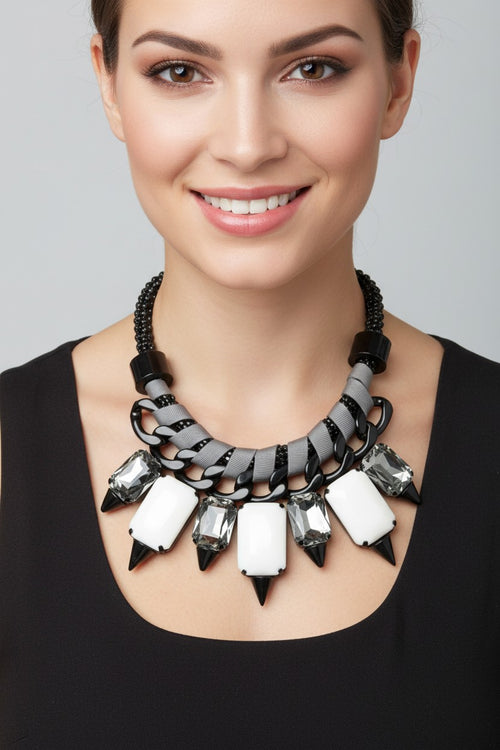 Chunky black chain statement necklace interwoven with grey ribbon trim featuring smoky faceted crystals and stark white resin stones