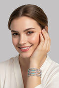 A close-up view of a smiling model wearing a wide multi-strand silver rhinestone cage bracelet detailed with rows of turquoise, lavender, and pink beads.