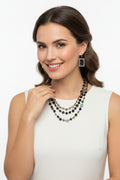 Model wearing a glamorous three strand black and smoky quartz faceted crystal statement necklace with a white dress