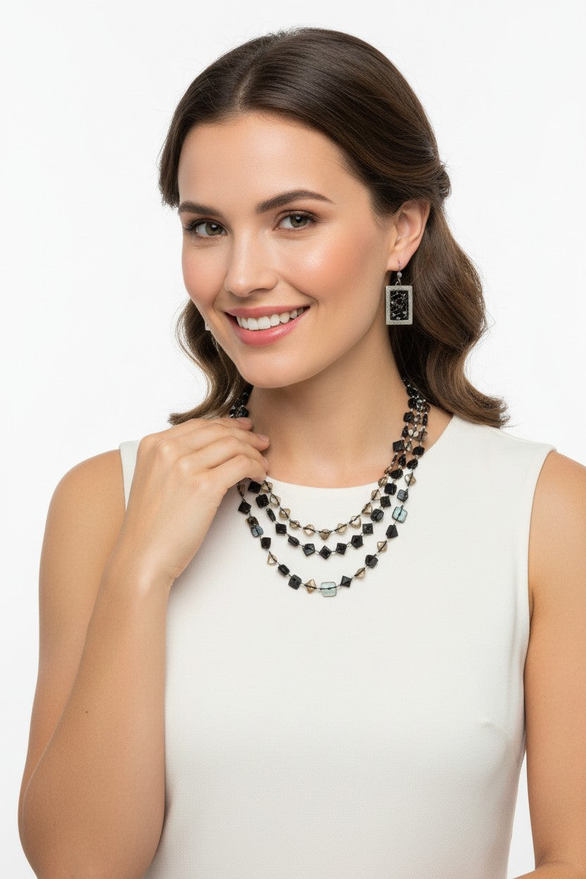 Model wearing a glamorous three strand black and smoky quartz faceted crystal statement necklace with a white dress