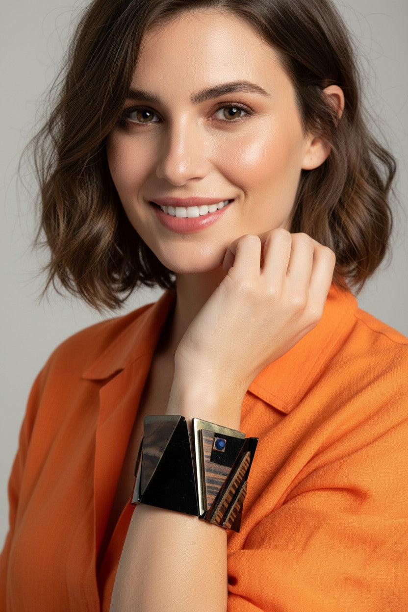  A close-up view of a smiling model wearing a wide architectural stretch bracelet featuring dramatic black triangular wood panels and iridescent shell details.