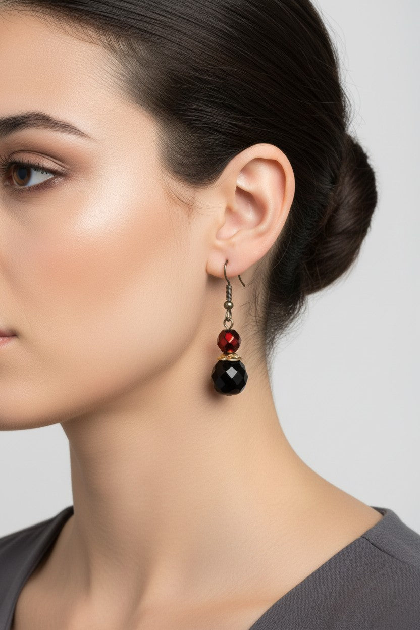 Side profile of a model wearing a unique pair of Australian Made drop earrings featuring faceted metallic red and jet black crystal beads.