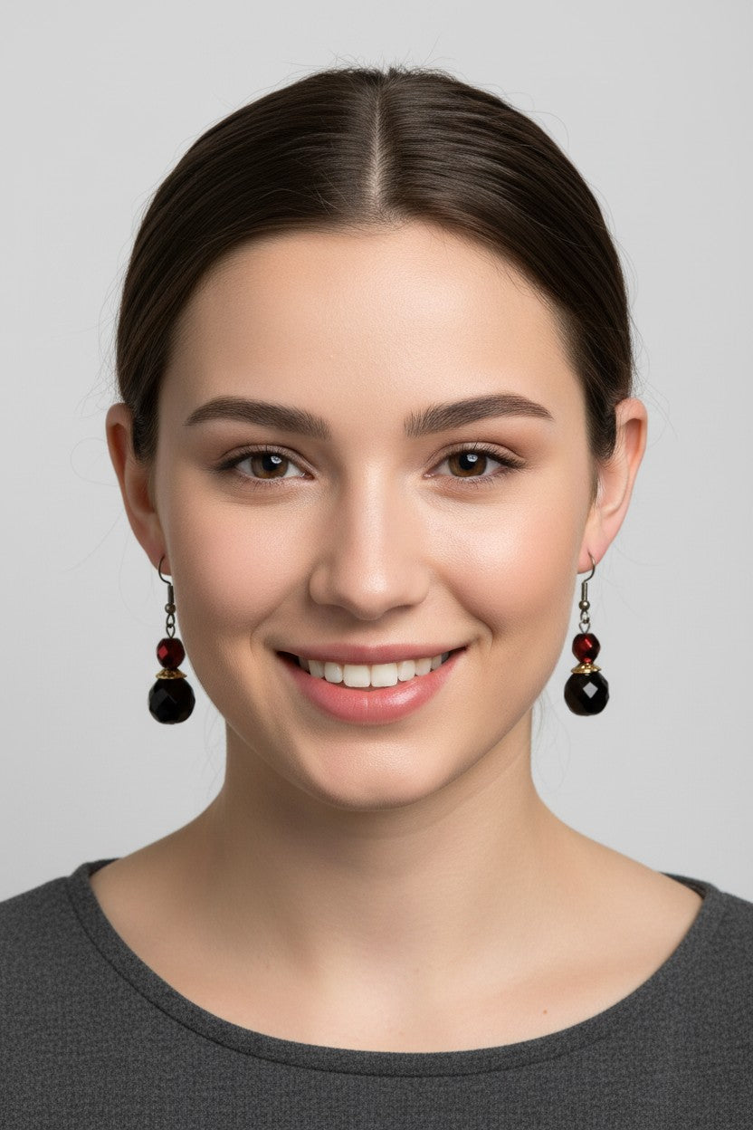 Front profile of a model with dark hair up wearing a unique pair of Australian Made drop earrings featuring faceted metallic red and jet black crystal beads.