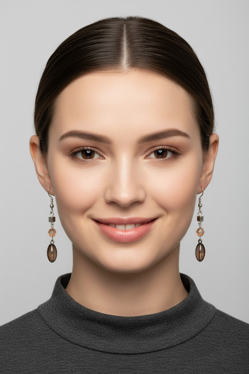front profile view of a model wearing a unique Australian Made silver plated drop earring adorned with a faceted amber Swarovski crystal and a smoky brown oval bead.