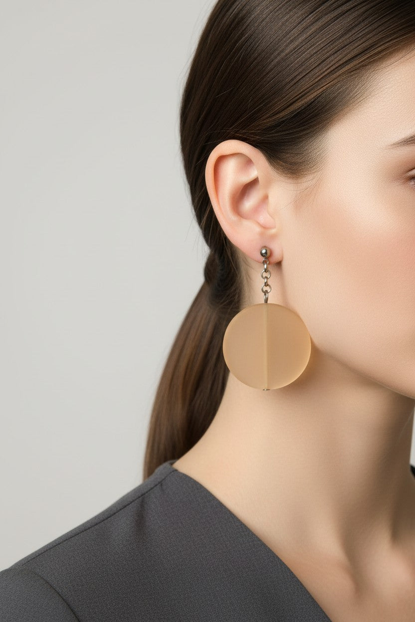 Side profile of a model wearing a pair of Australian Made silver plated chain drop earrings featuring large frosted beige circular disc beads.
