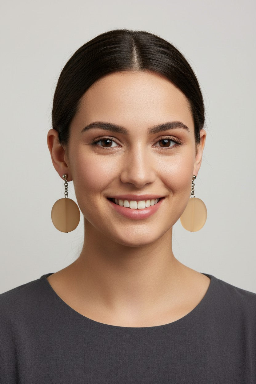 front profile of a model wearing a pair of Australian Made silver plated chain drop earrings featuring large frosted beige circular disc beads.