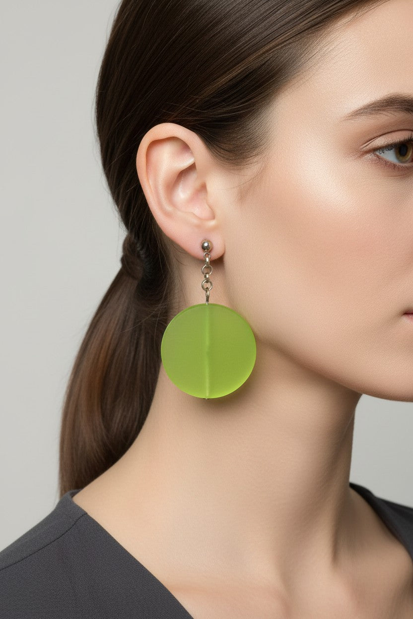 Side profile of a model wearing a pair of Australian Made silver plated chain drop earrings featuring large frosted lime green circular disc beads.
