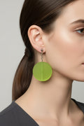 Side profile of a model wearing a pair of Australian Made silver plated chain drop earrings featuring large frosted lime green circular disc beads.