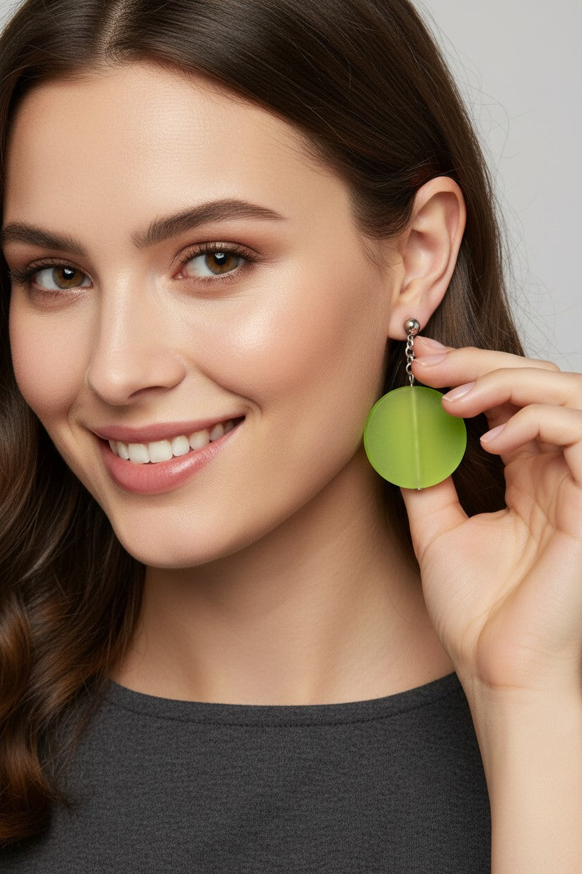 close up profile of a model touching her earring wearing a pair of Australian Made silver plated chain drop earrings featuring large frosted beige circular disc beads.