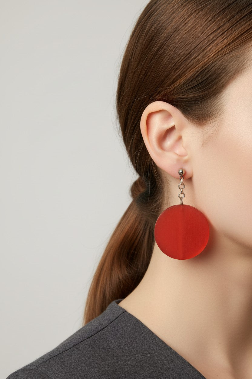 Side profile of a model wearing a pair of Australian Made silver plated chain drop earrings featuring large translucent frosted red circular disc beads.