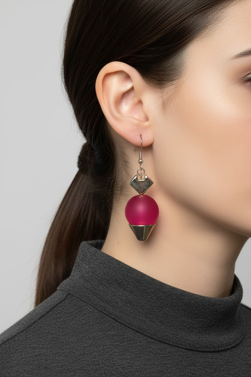 Close up profile view of a model wearing a pair of Australian Made silver plated drop earrings featuring a singular smooth matte magenta ball charm.
