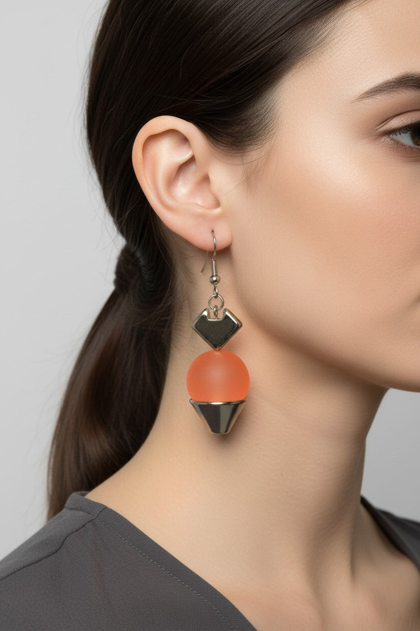 Side profile view of a woman wearing a pair of Australian Made silver plated drop earrings featuring a smooth matte orange ball charm.