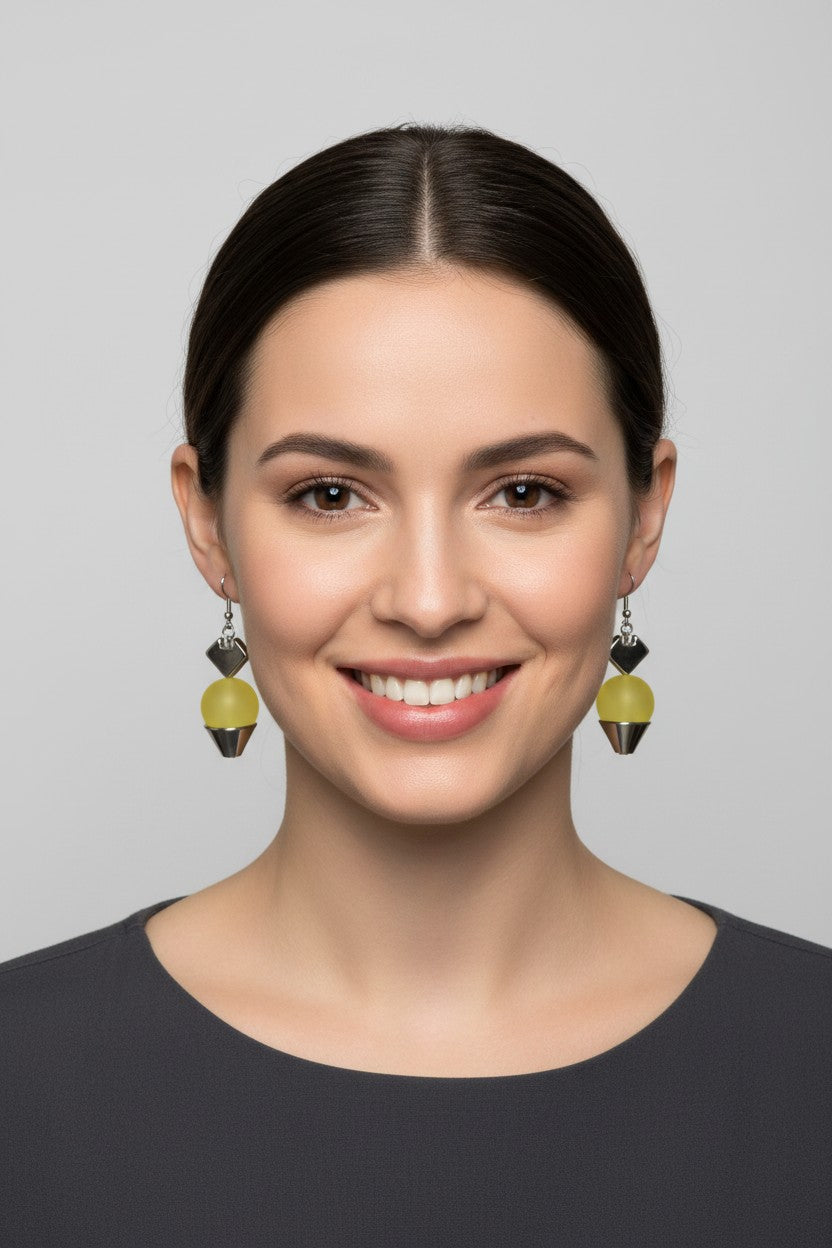 front profile of a model wearing a pair of Australian Made silver plated drop earrings featuring a singular smooth matte yellow ball charm.