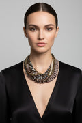 Studio portrait of a model wearing a unique Australian Made statement bronze necklace featuring crystals, pearls, and chains on a slate ribbon.