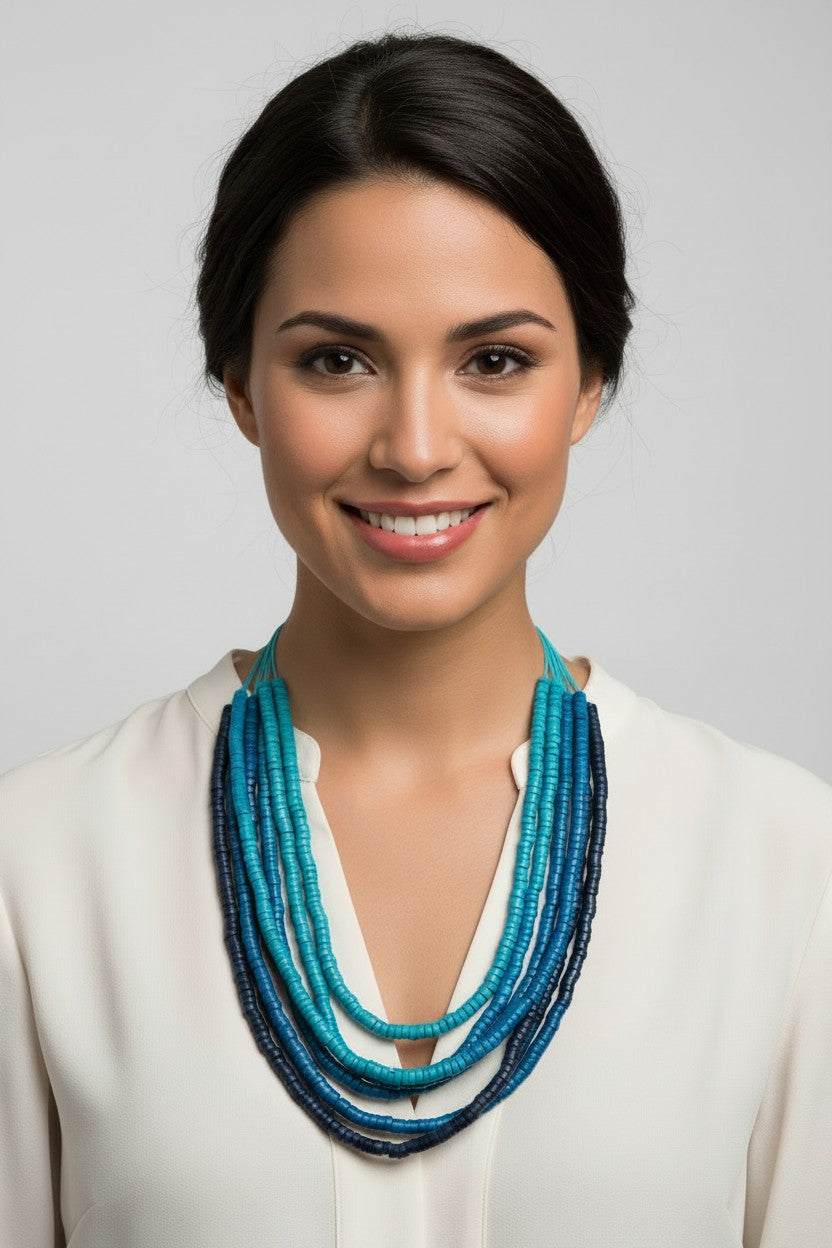 Long multi-strand beaded necklace with varying blue tones on multiple blue cords against a light grey background.