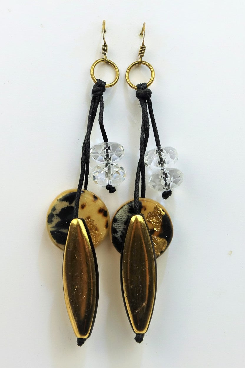 Long bohemian drop earrings for pierced ears featuring black cords, faceted clear beads, leopard print circular discs, and smooth metallic gold oval beads.