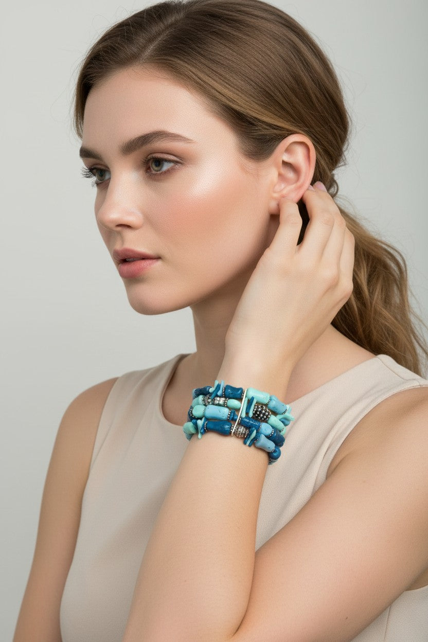 Side view of a model wearing a turquoise multi strand stretch bracelet featuring a stacked layout of blue beads and silver plated spacer accents.