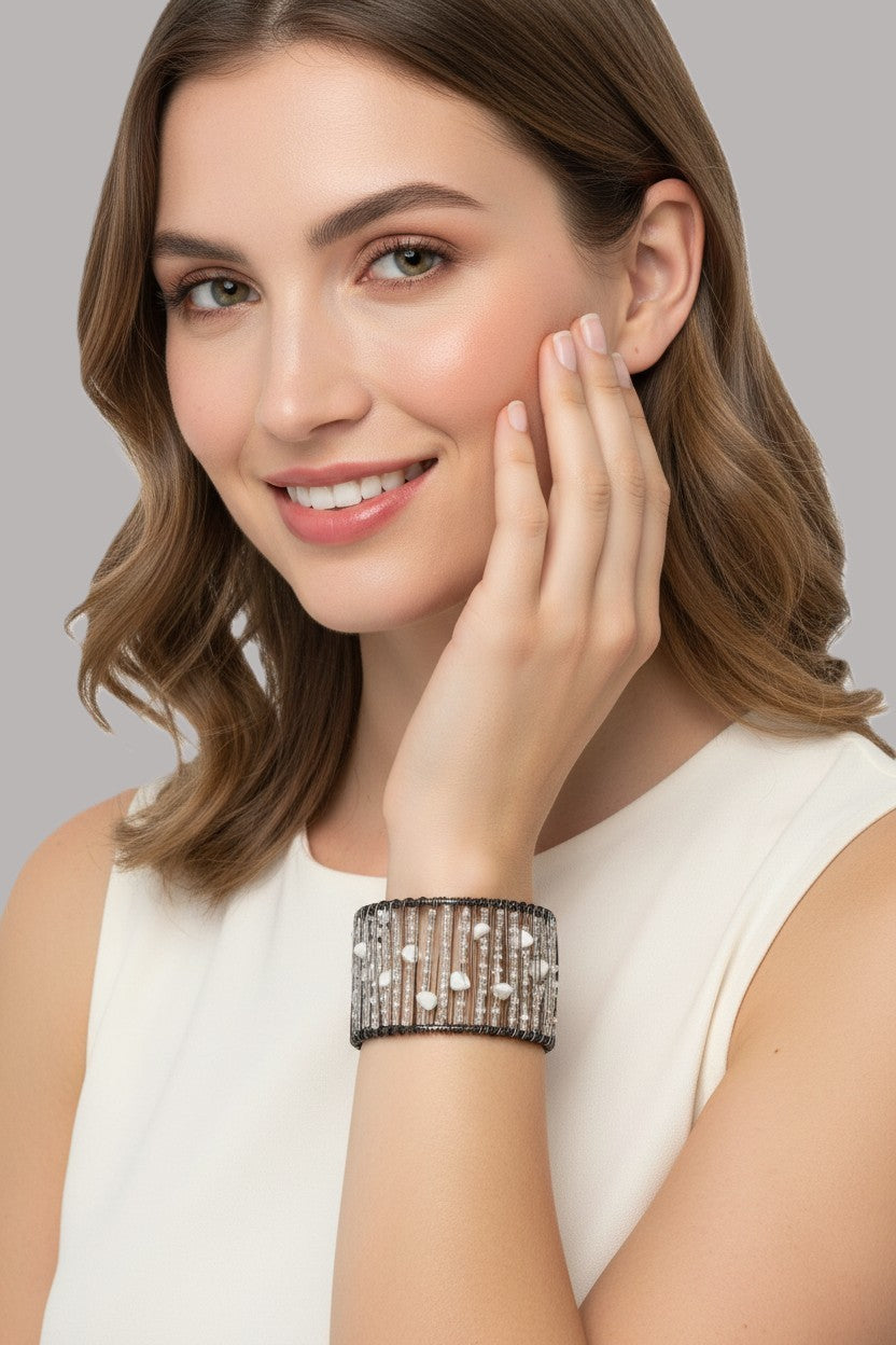 A close-up view of a model wearing a wide multi-strand dark wire cuff bracelet detailed with clear micro-beads and tumbled white semi-precious stones.