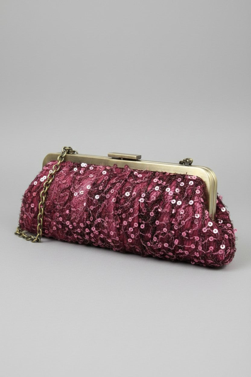 A textured magenta evening clutch bag featuring a satin base, matching sequin-embellished netting overlay, an antique bronze metal frame, and a chain shoulder strap.