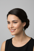 Woman with updo hairstyle smiling while wearing elegant gunmetal drop earrings with a crystal pendant and fine chain tassels.