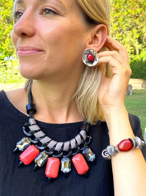 Chunky black metallic curb chain statement necklace interwoven with grey grosgrain ribbon, faceted black crystals, and bright red resin stones on a model