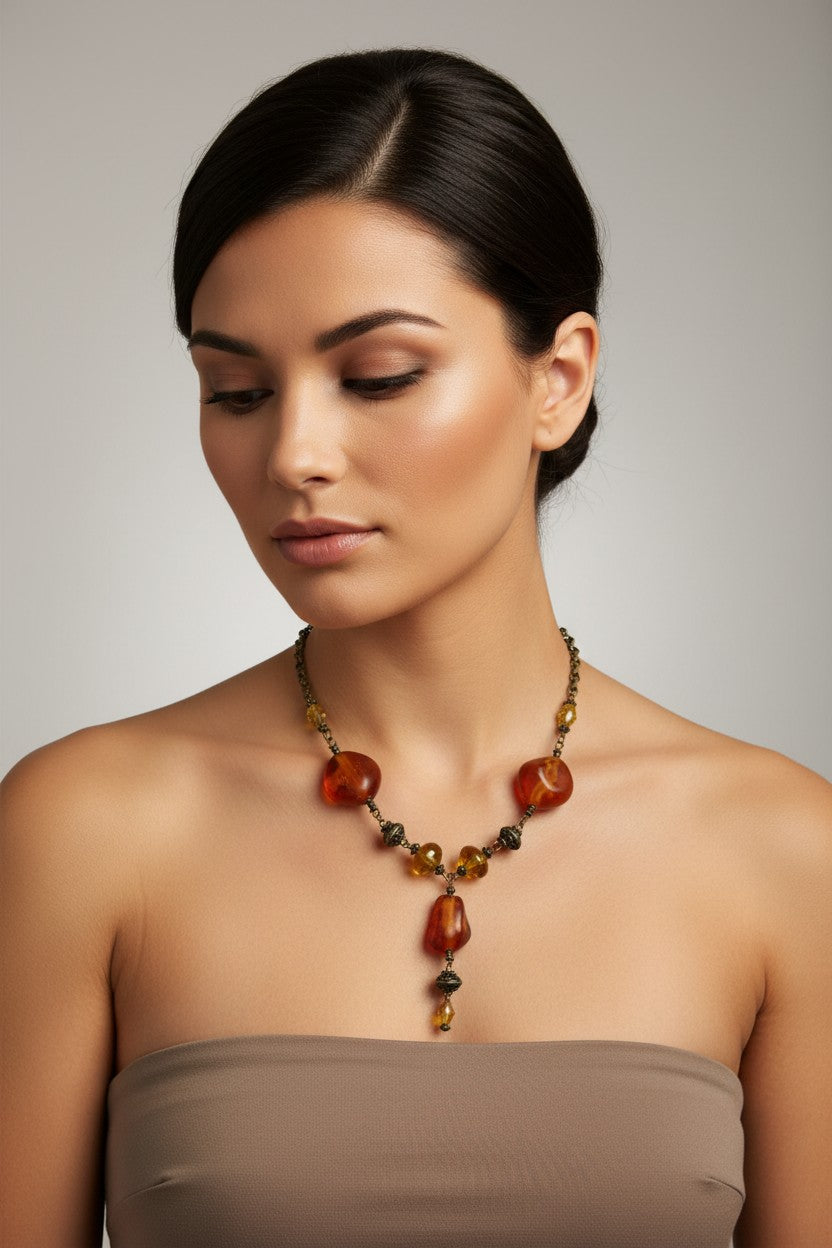 Model wearing a vintage style necklace featuring large translucent amber-coloured organic beads and intricate bronze metallic details on a delicate chain.